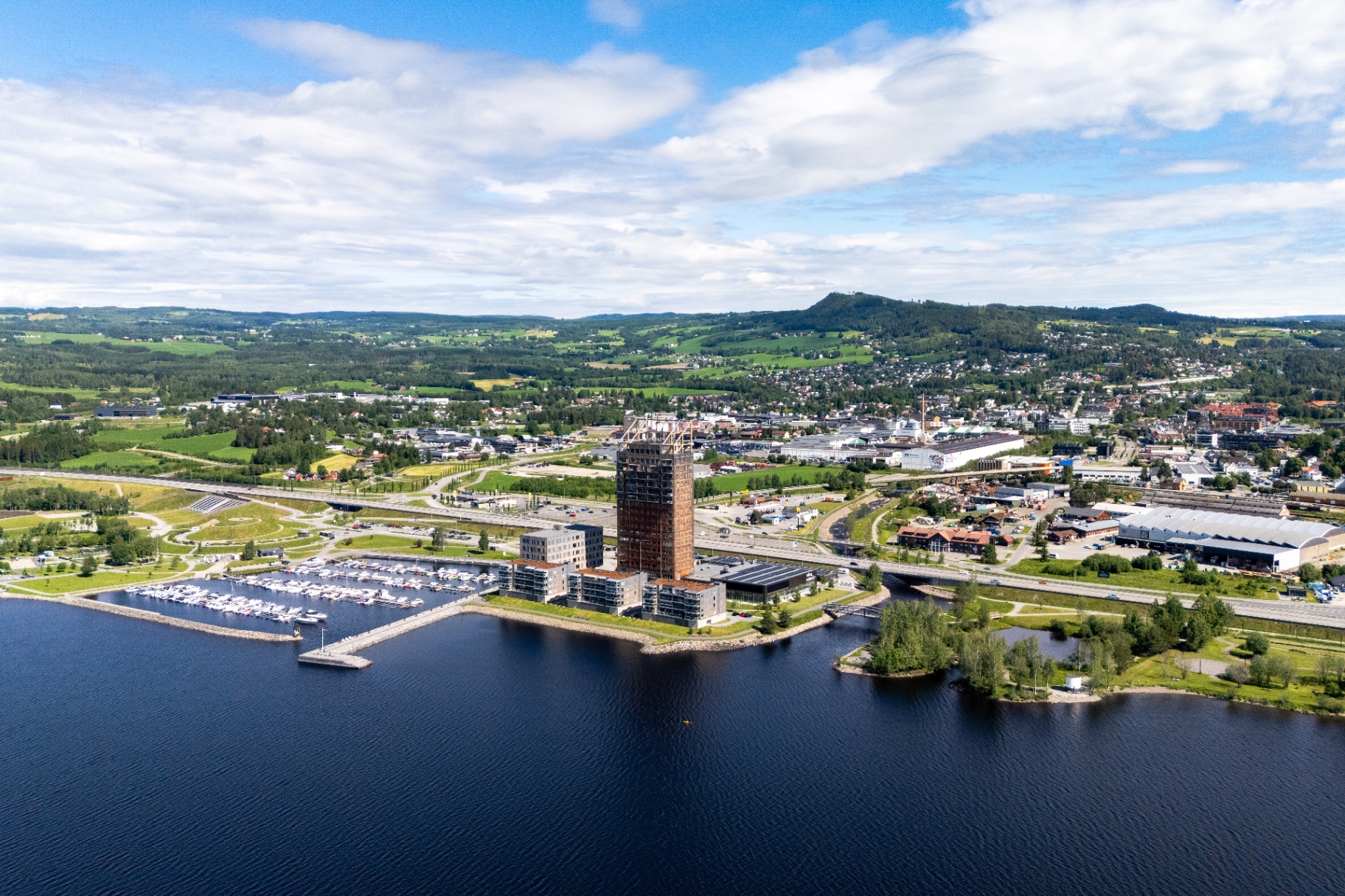 Luftfoto av Brumunddal sentrum med Mjøsa, marina og det grønne kulturlandskapet